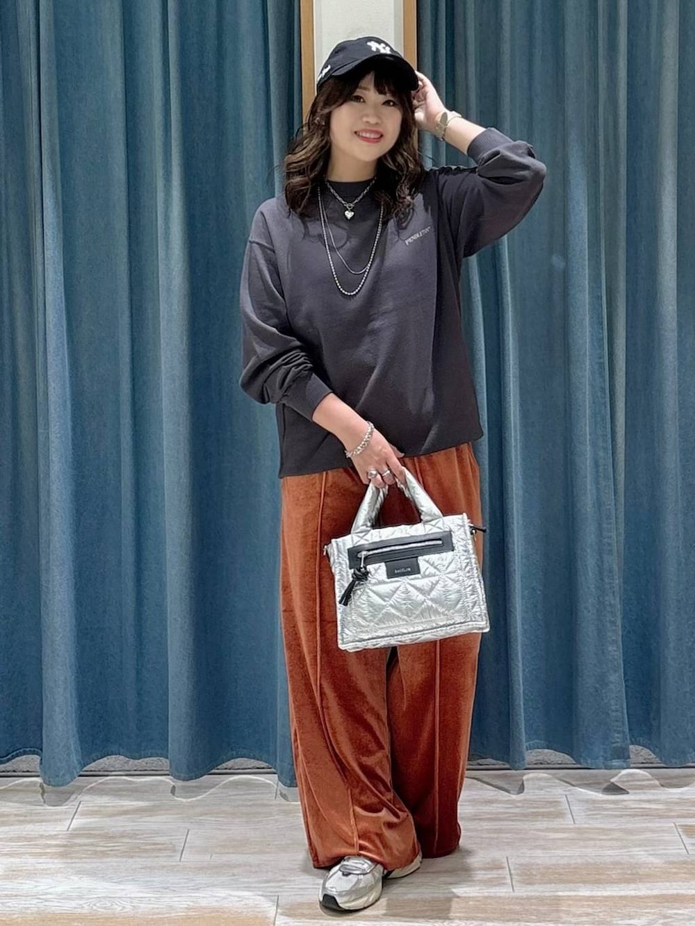 シルバー系のショルダーバッグ、ブラック系のスウェット、レッド系のその他パンツを着用したレディースの秋コーディネートの2枚目の写真