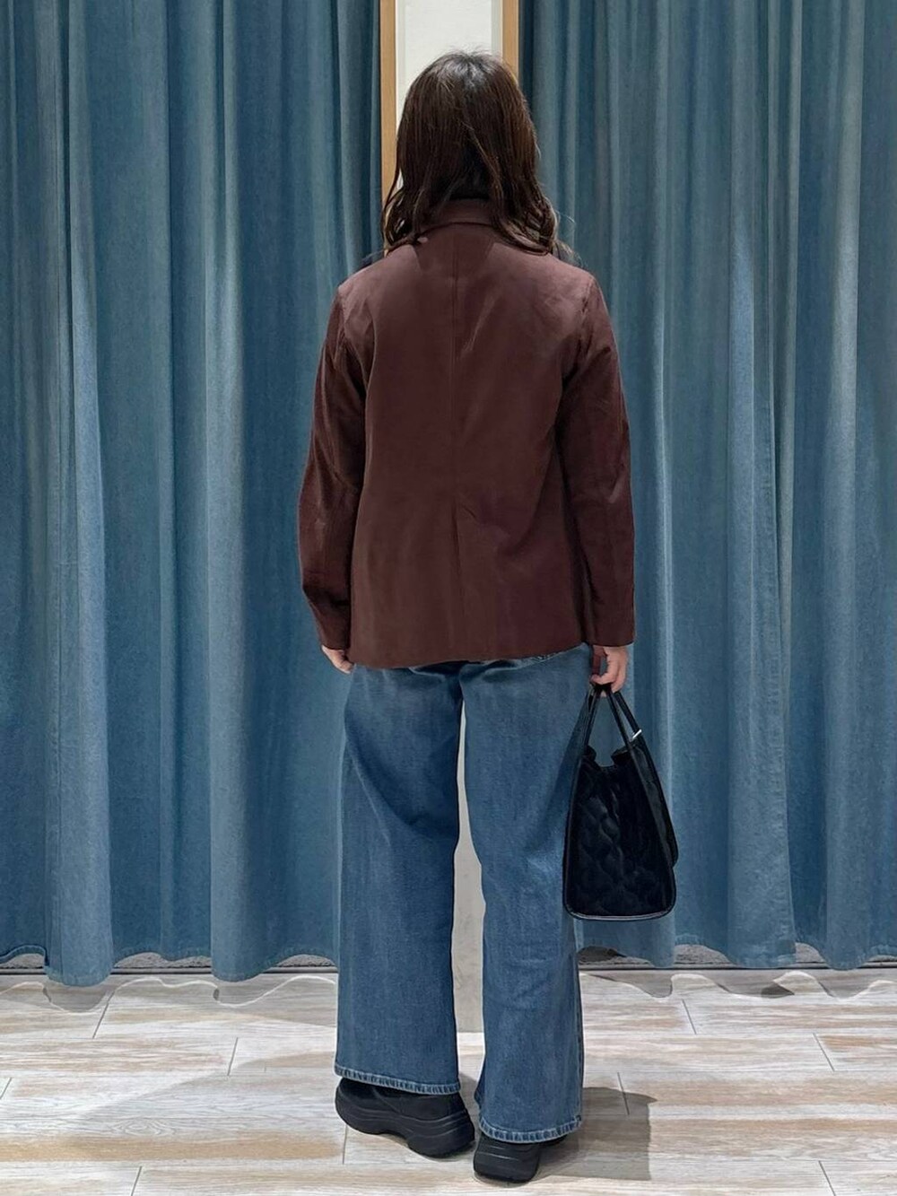 ブラック系のブーツ、ブラウン系のテーラードジャケット、ブルー系のデニムパンツを着用したレディースの秋コーディネートの3枚目の写真