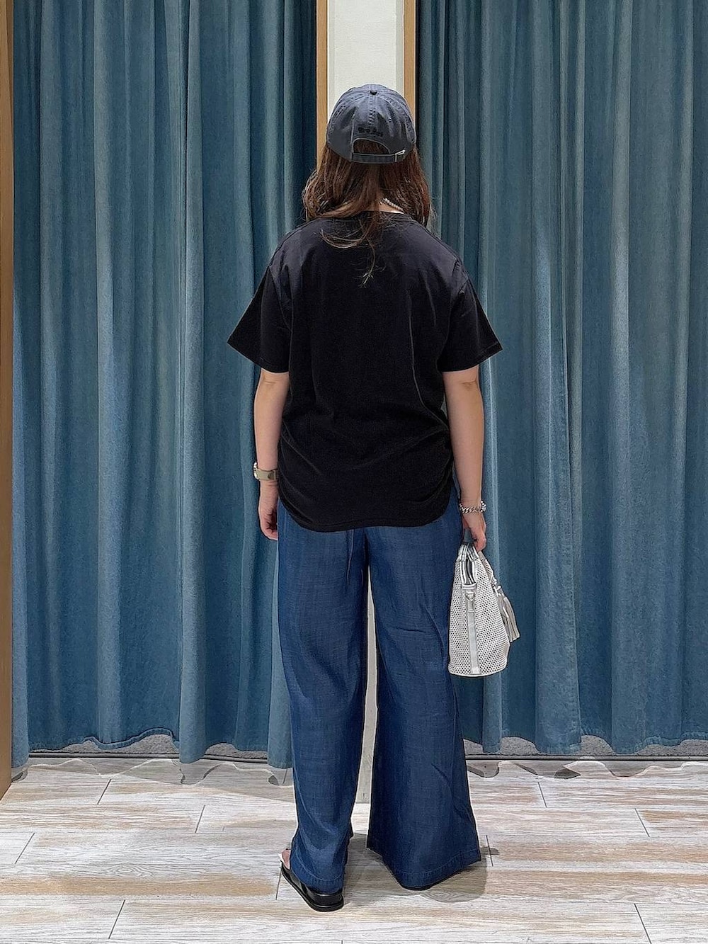 ブルー系のデニムパンツ、グレー系のショルダーバッグ、ブラック系のサンダルを着用したレディースの夏コーディネートの3枚目の写真