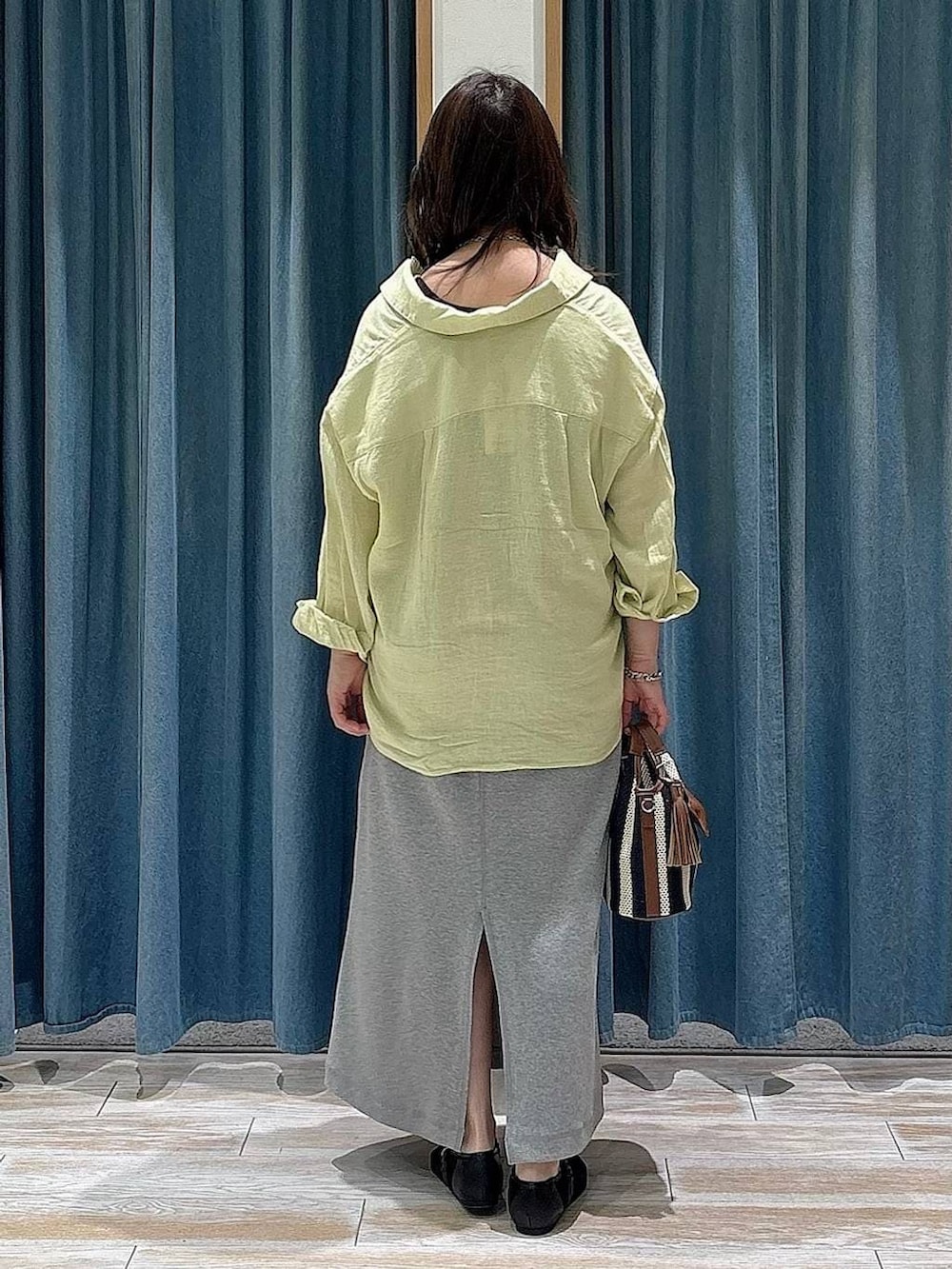 イエロー系のシャツ/ブラウス、ブラック系のパンプス、ブルー系のショルダーバッグを着用したレディースの春コーディネートの3枚目の写真