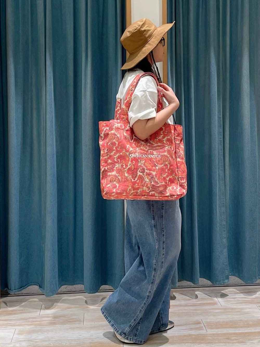 ブルー系のデニムパンツ、ホワイト系のTシャツ/カットソー、レッド系のトートバッグを着用したレディースの春コーディネートの2枚目の写真