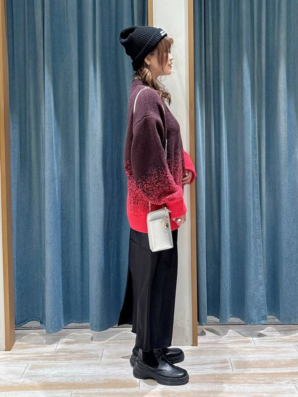 ブラック系のブーツ、ブラック系のスカート、ピンク系のニット/セーターを着用したレディースの秋コーディネートの2枚目の写真