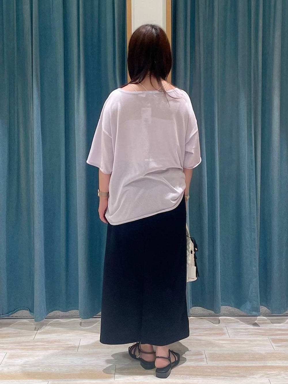 ホワイト系のハンドバッグ、ブラック系のスカート、パープル系のニット/セーターを着用したレディースの春コーディネートの3枚目の写真