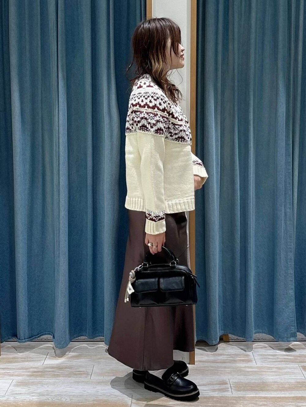 ブラック系のボストンバッグ、ブラック系のローファー、ホワイト系のニット/セーターを着用したレディースの秋コーディネートの2枚目の写真