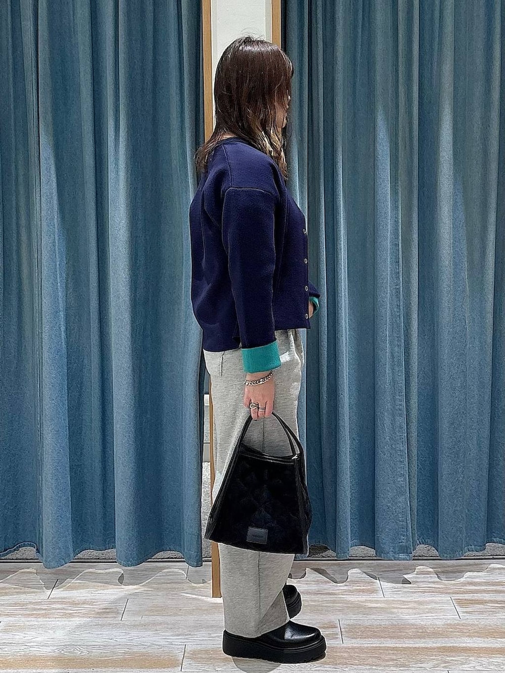 ブラック系のブーツ、ブラック系のハンドバッグ、ブルー系のカーディガン/ボレロを着用したレディースの冬コーディネートの2枚目の写真