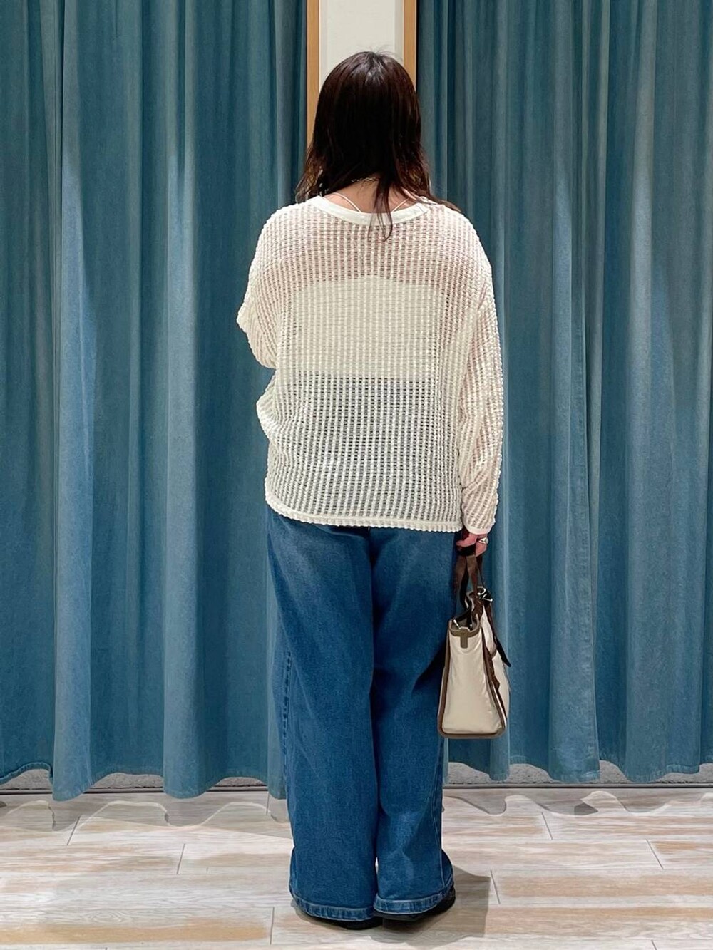ホワイト系のキャミソール、ブルー系のデニムパンツ、ベージュ系のトートバッグを着用したレディースの春コーディネートの3枚目の写真