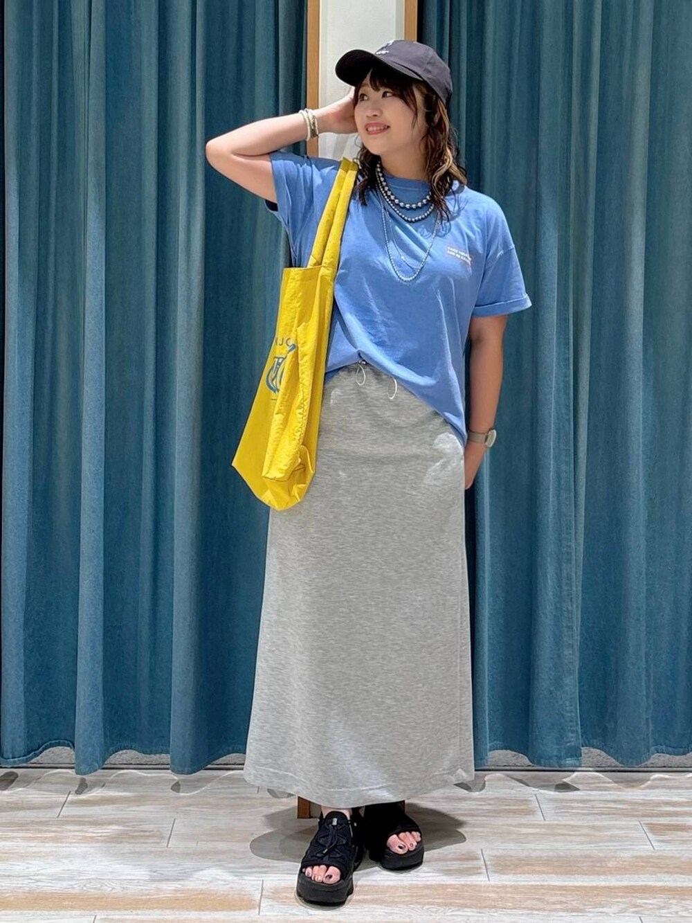 ブルー系のTシャツ/カットソー、イエロー系のトートバッグ、グレー系のスカートを着用したレディースの夏コーディネートの4枚目の写真