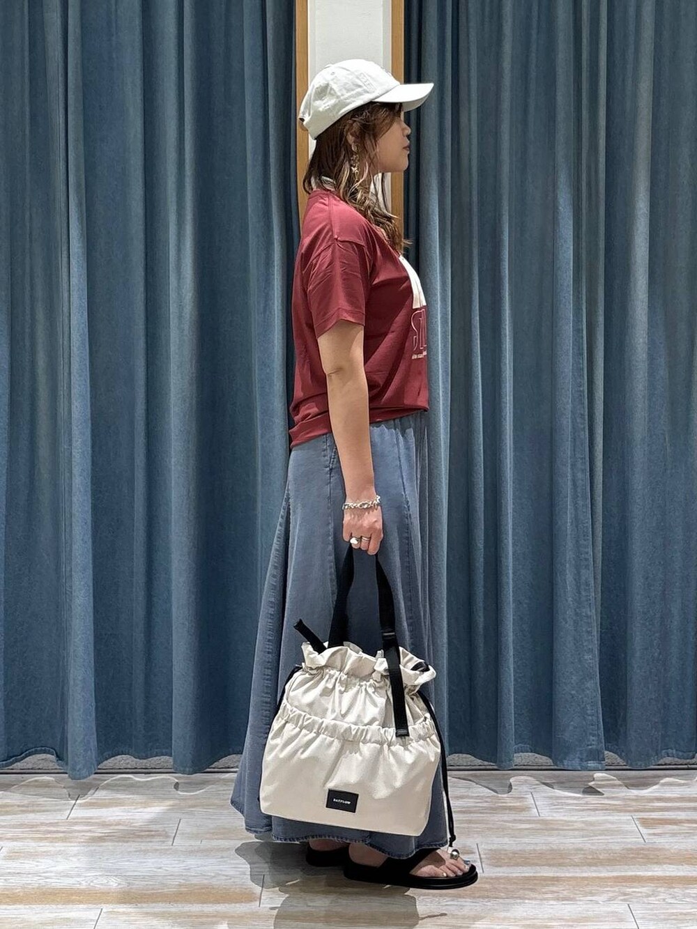 ホワイト系のトートバッグ、レッド系のTシャツ/カットソー、ブラック系のサンダルを着用したレディースの夏コーディネートの2枚目の写真