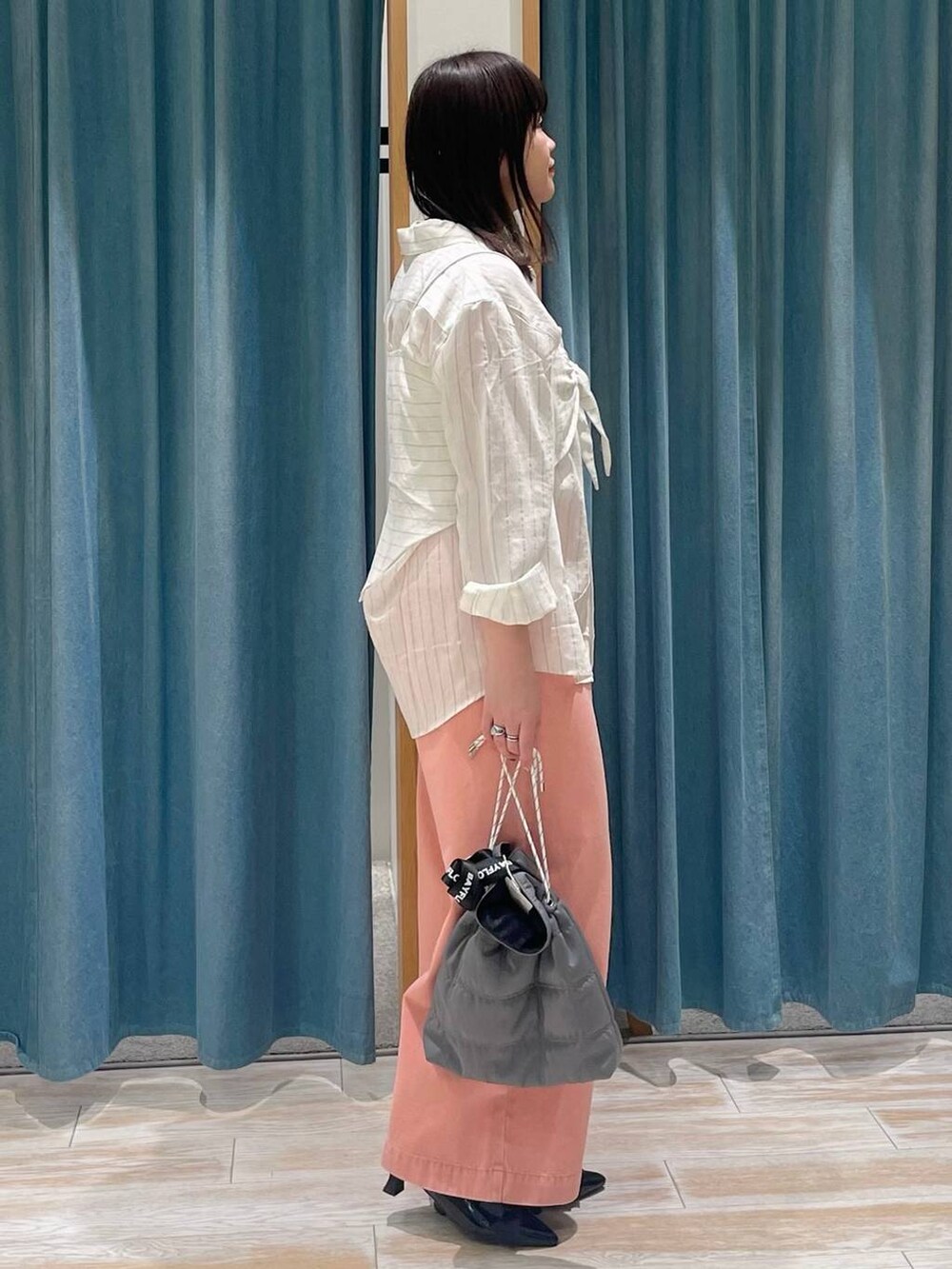 ブラック系のパンプス、グレー系のショルダーバッグ、ピンク系のデニムパンツを着用したレディースの冬コーディネートの2枚目の写真