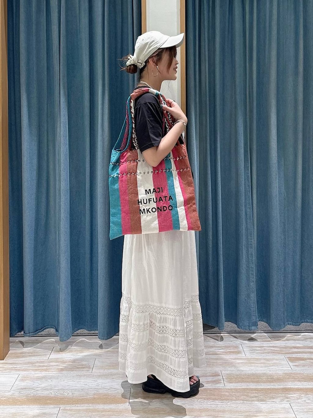 ホワイト系のスカート、ピンク系のトートバッグ、ブラック系のTシャツ/カットソーを着用したレディースの春コーディネートの2枚目の写真