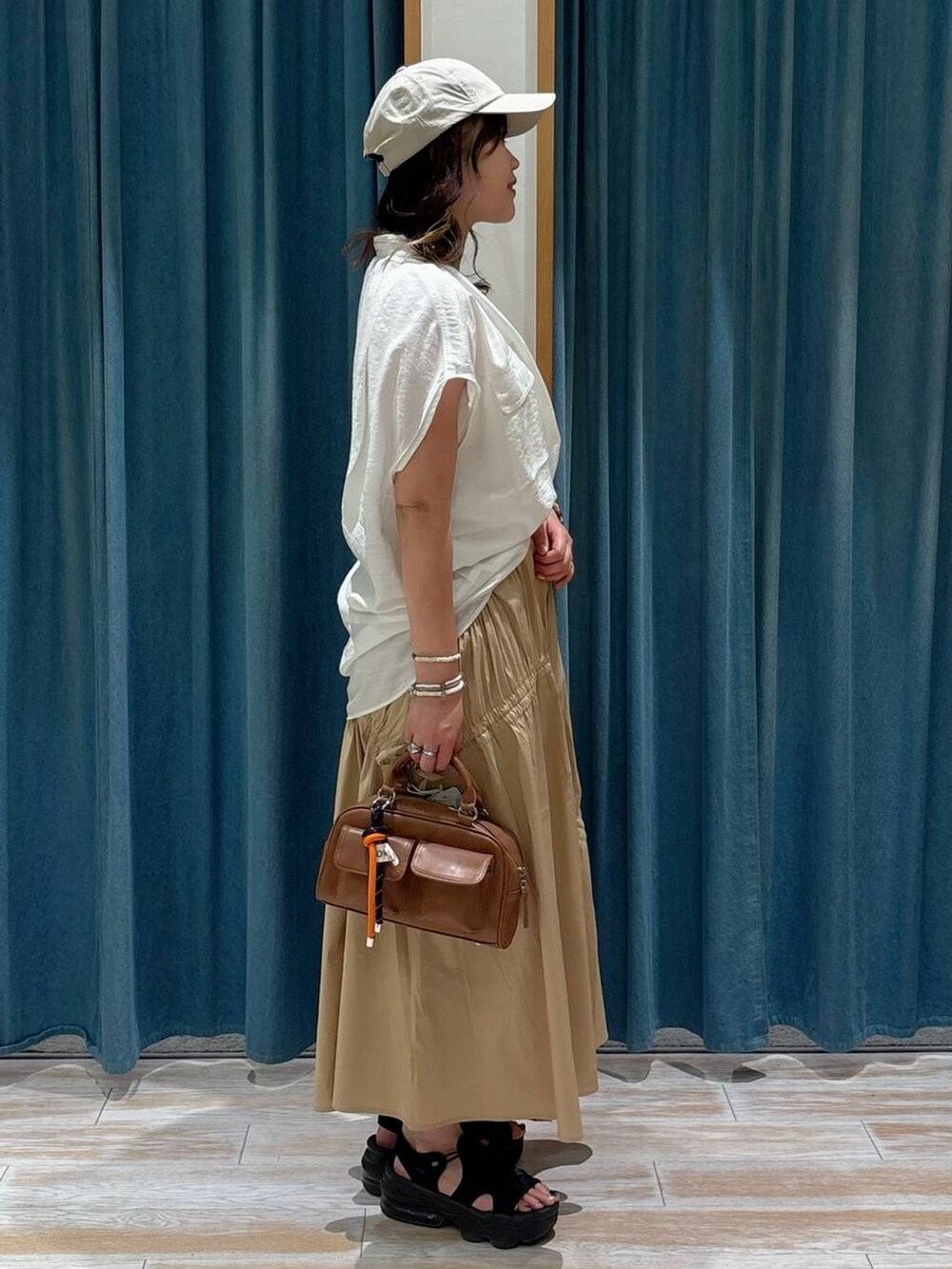 ホワイト系のキャミソール、ホワイト系のシャツ/ブラウス、ブラウン系のボストンバッグを着用したレディースの夏コーディネートの2枚目の写真