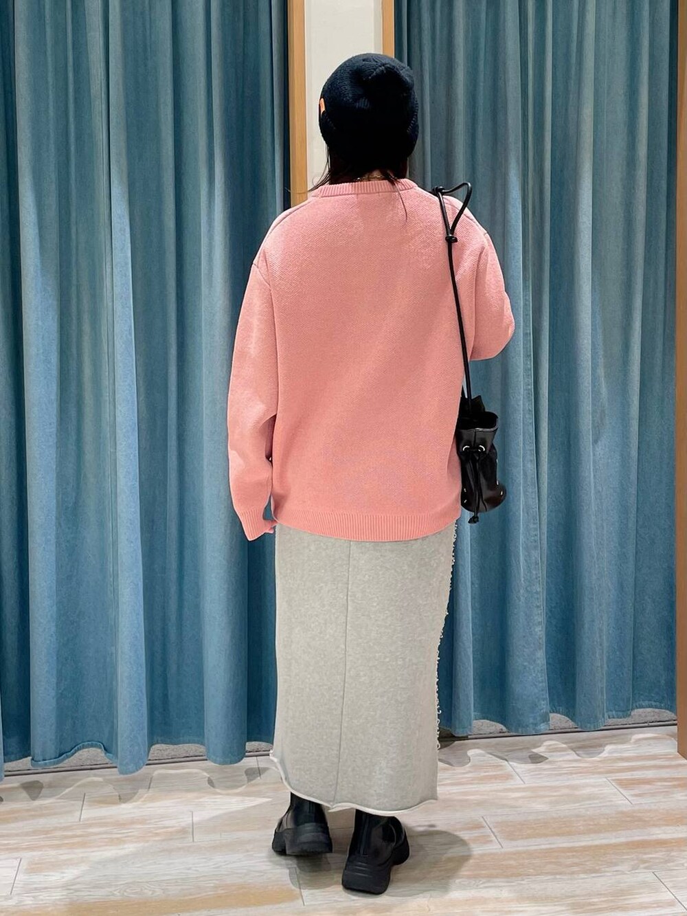 ピンク系のニット/セーター、ブラック系のショルダーバッグ、ブラック系のブーツを着用したレディースの冬コーディネートの2枚目の写真