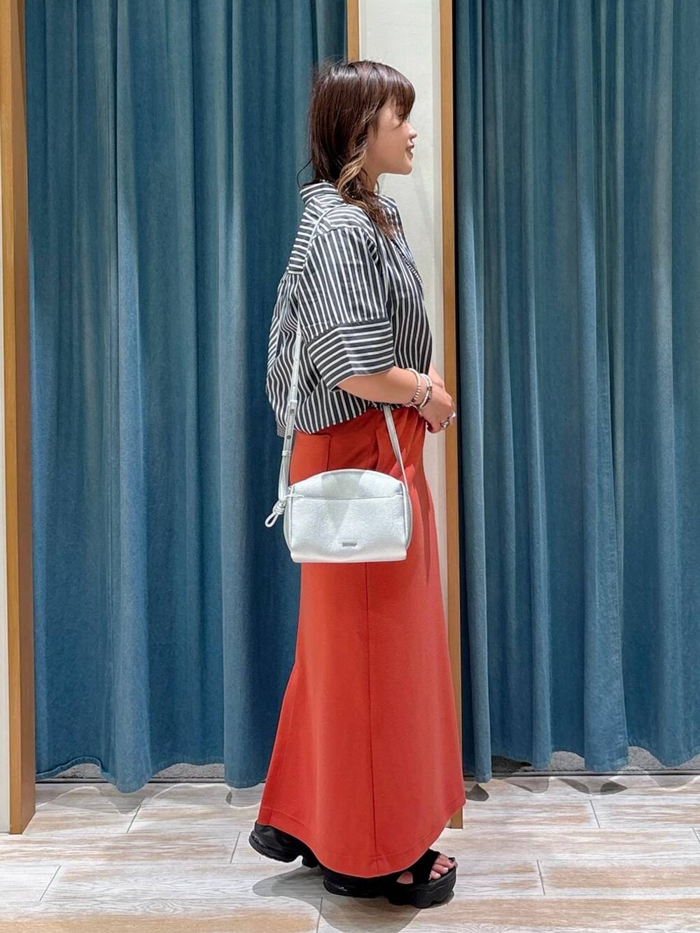 ブラック系のキャミソール、レッド系のスカート、シルバー系のショルダーバッグを着用したレディースの夏コーディネートの2枚目の写真