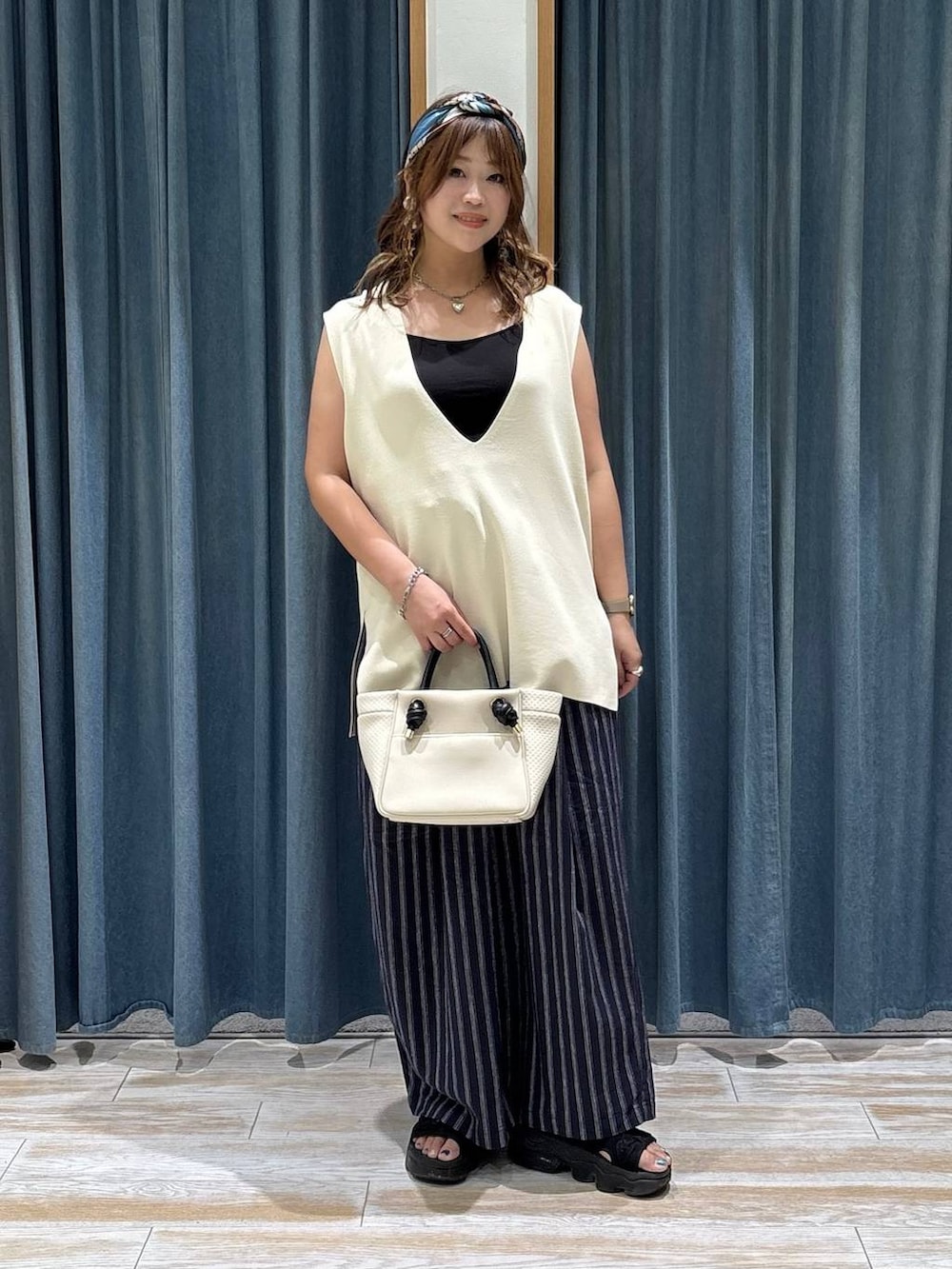 ブルー系のその他パンツ、ベージュ系のショルダーバッグ、ホワイト系のニット/セーターを着用したレディースの夏コーディネートの2枚目の写真