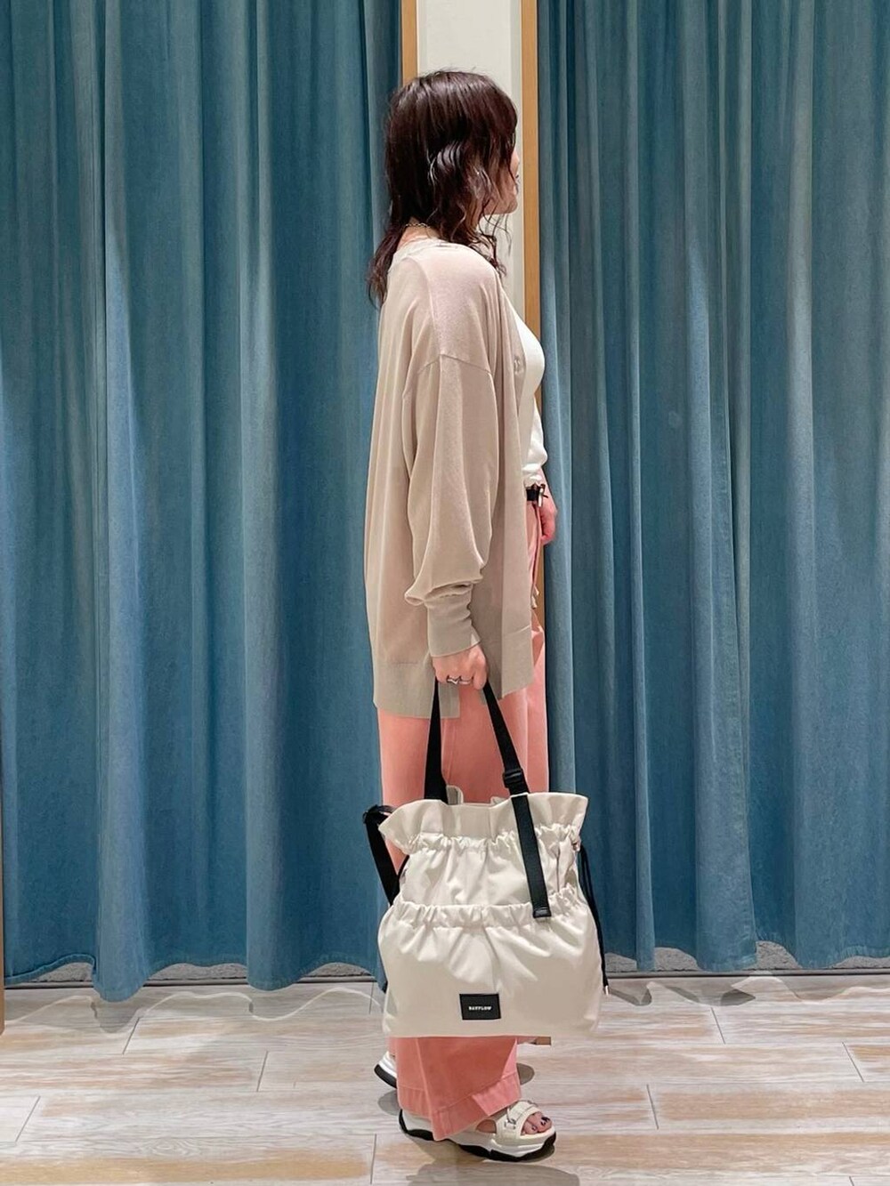 ホワイト系のキャミソール、ホワイト系のトートバッグ、ピンク系のデニムパンツを着用したレディースの春コーディネートの2枚目の写真