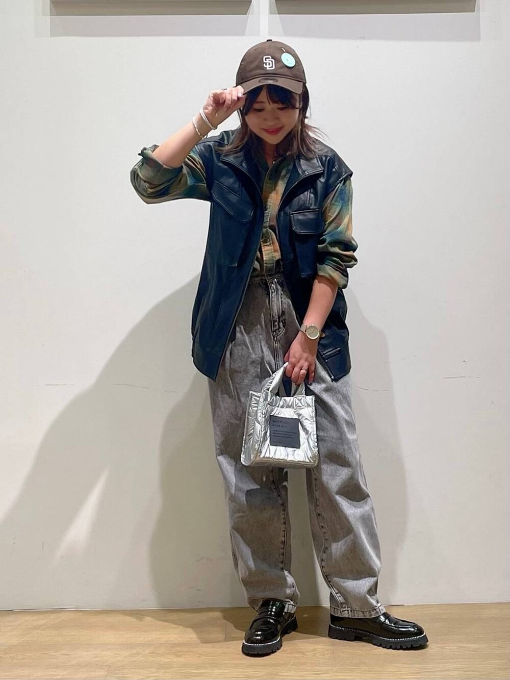 シルバー系のショルダーバッグ、ブラック系のローファー、ブラック系のデニムパンツを着用したレディースの秋コーディネートの2枚目の写真