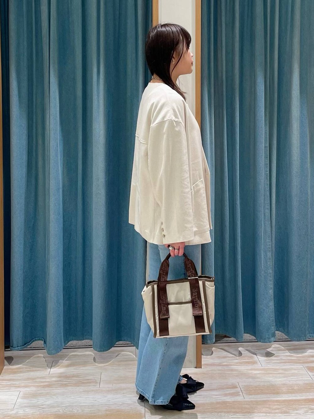 ブラック系のパンプス、イエロー系のTシャツ/カットソー、ブルー系のデニムパンツを着用したレディースの春コーディネートの2枚目の写真