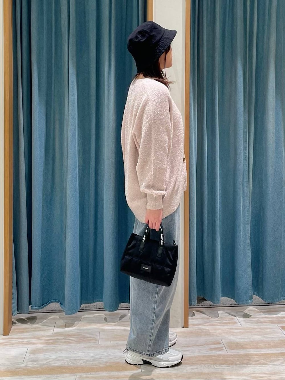 ブルー系のデニムパンツ、ブラック系のショルダーバッグ、ホワイト系のスニーカーを着用したレディースの冬コーディネートの2枚目の写真