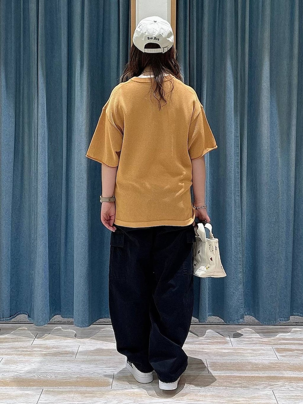 ホワイト系のスニーカー、ベージュ系のトートバッグ、ブラック系のカーゴパンツを着用したレディースの春コーディネートの2枚目の写真