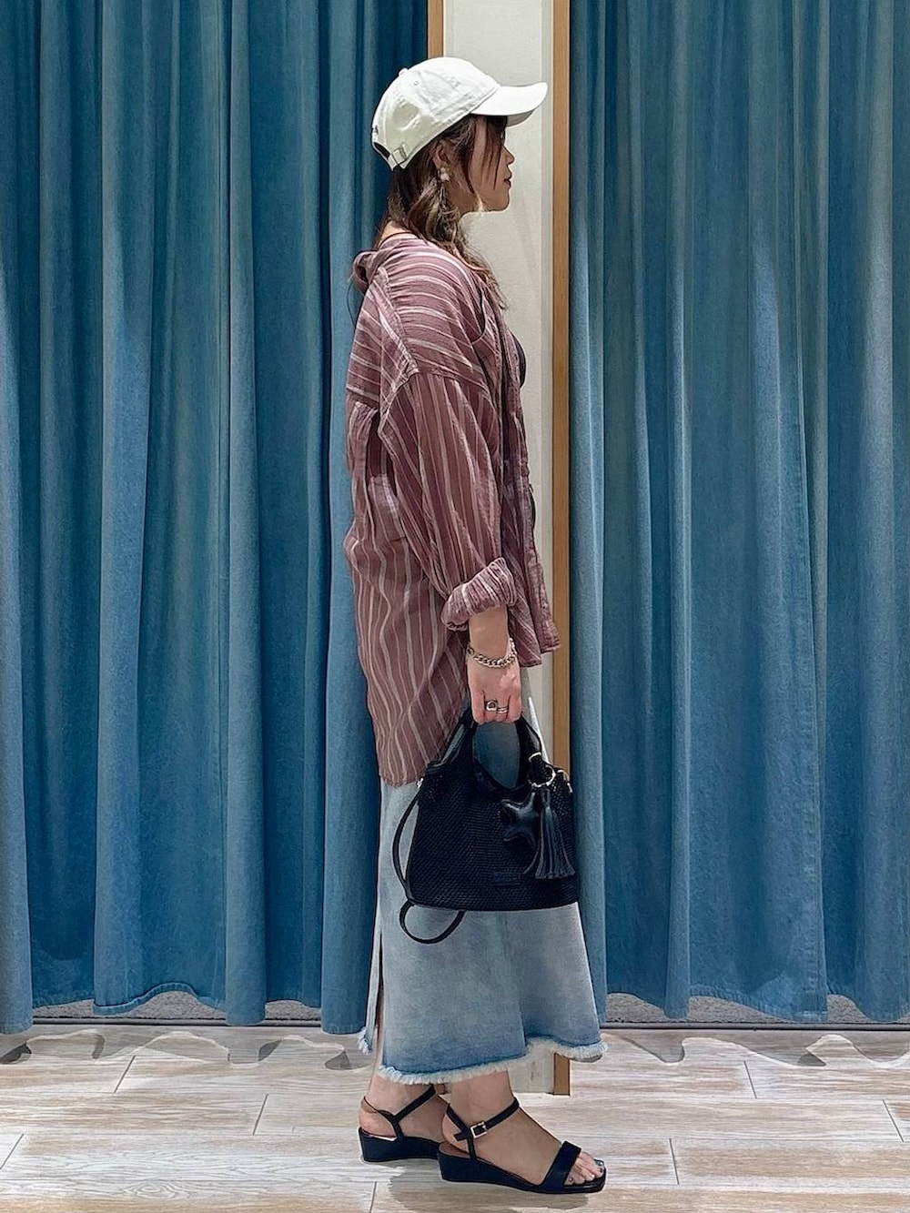 ブラウン系のシャツ/ブラウス、ブルー系のデニムスカート、ブラック系のショルダーバッグを着用したレディースの春コーディネートの2枚目の写真