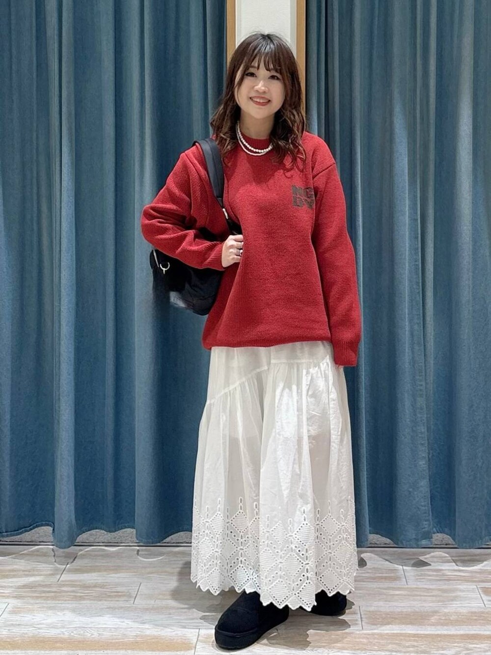 ブラック系のブーツ、ブラック系のバックパック/リュック、ホワイト系のスカートを着用したレディースの秋コーディネートの4枚目の写真