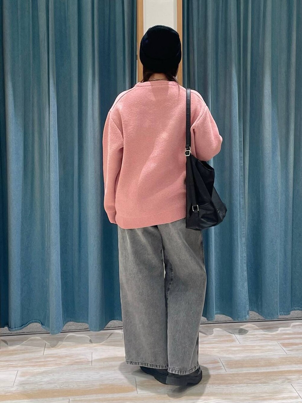 ピンク系のニット/セーター、ブラック系のショルダーバッグ、グレー系のデニムパンツを着用したレディースの冬コーディネートの3枚目の写真