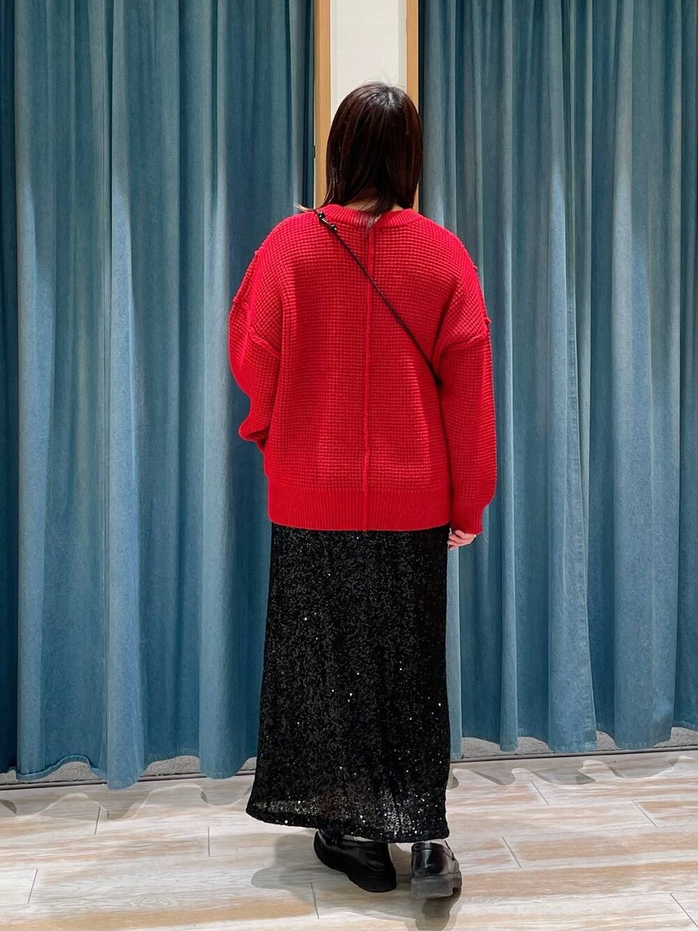 グレー系のショルダーバッグ、ブラック系のスカート、レッド系のニット/セーターを着用したレディースの冬コーディネートの3枚目の写真