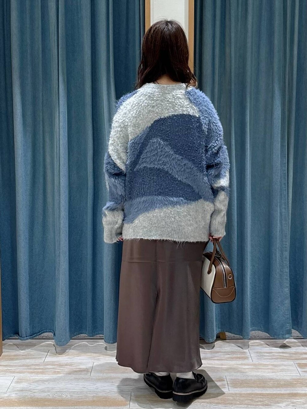 ホワイト系のハンドバッグ、ブラック系のローファー、ブルー系のカーディガン/ボレロを着用したレディースの秋コーディネートの3枚目の写真