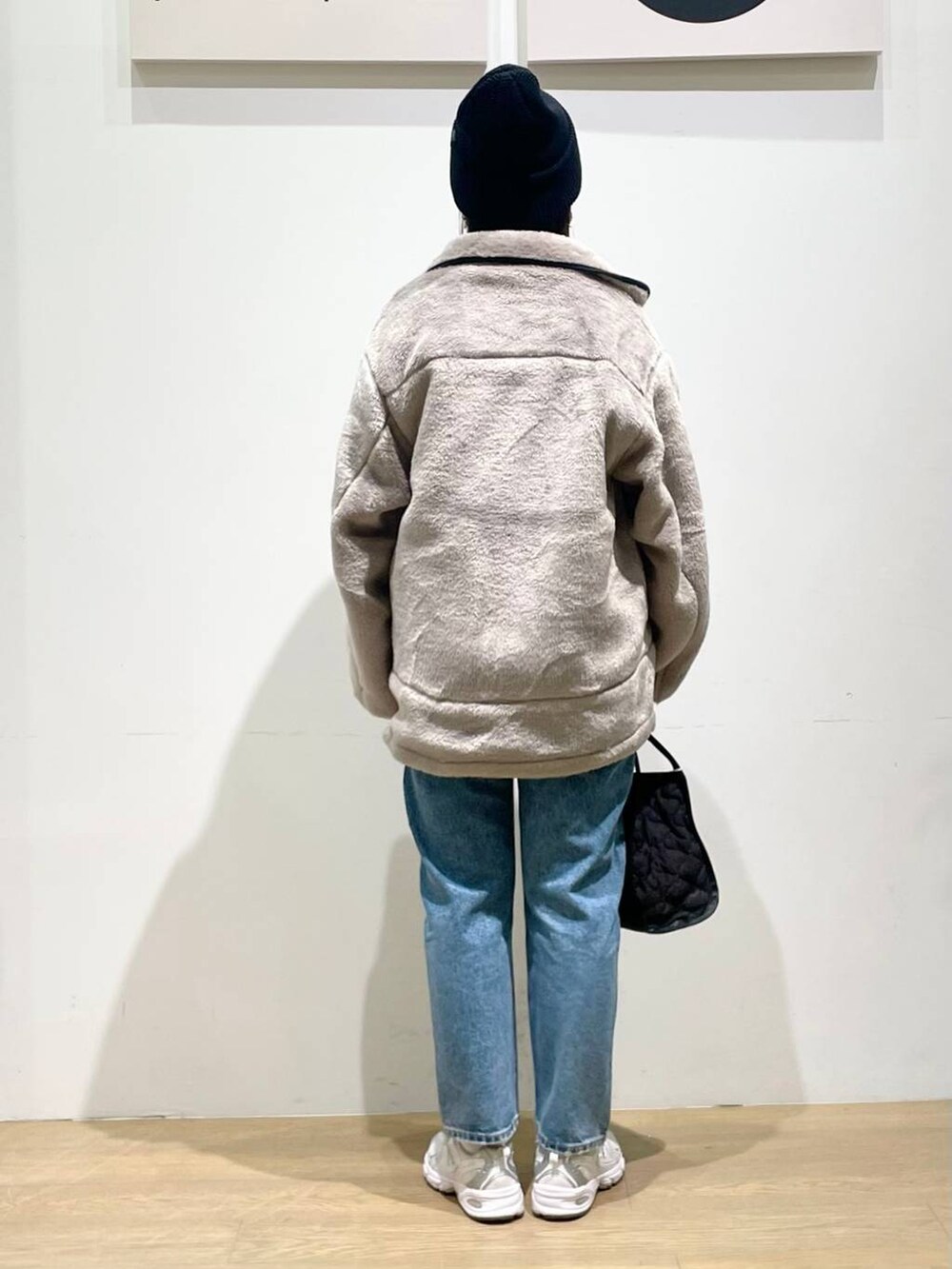 ベージュ系のブルゾン、ブラック系のハンドバッグ、ブルー系のデニムパンツを着用したレディースの秋コーディネートの3枚目の写真