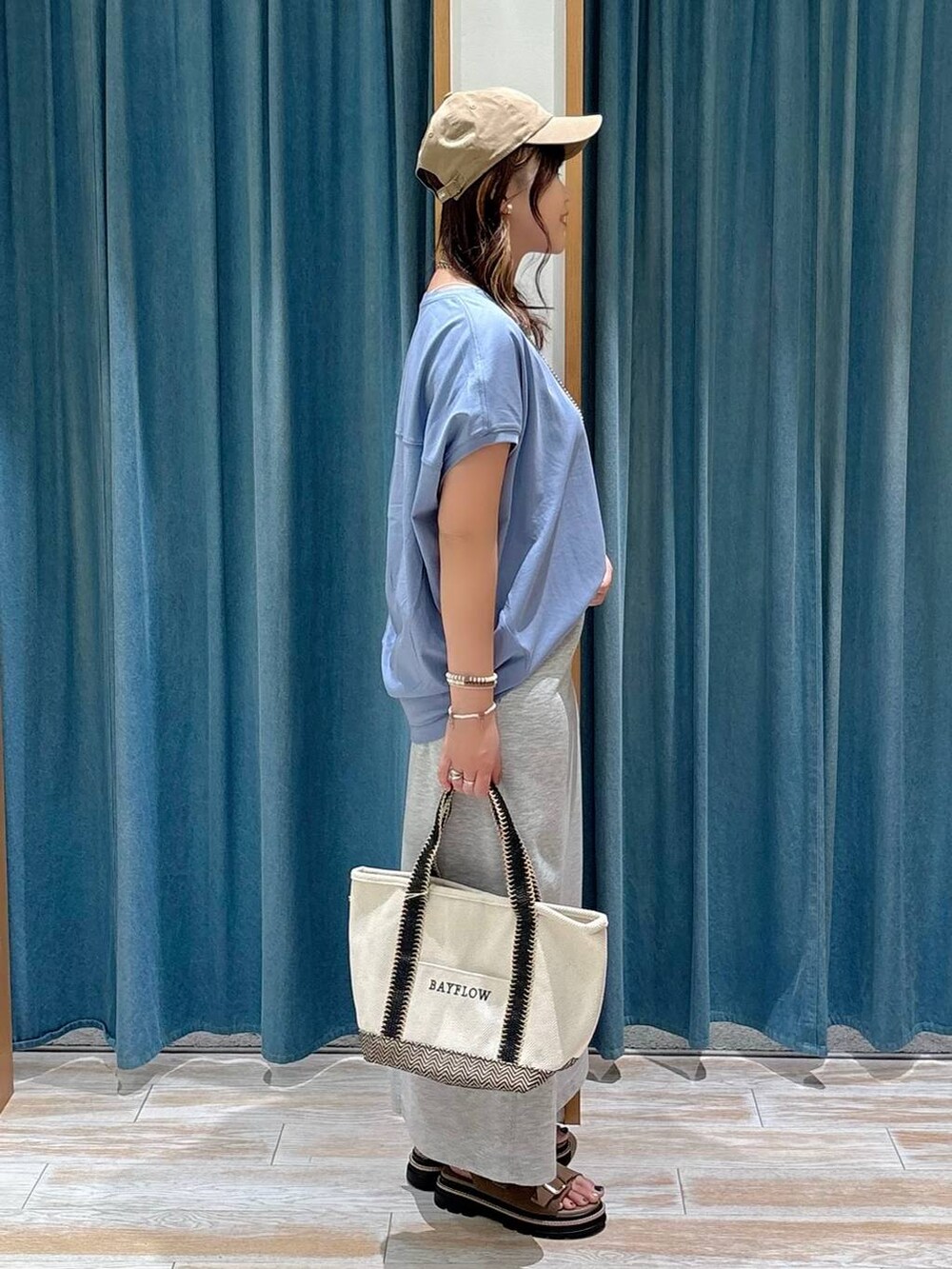ベージュ系のトートバッグ、ブルー系のTシャツ/カットソー、ベージュ系のサンダルを着用したレディースの夏コーディネートの2枚目の写真