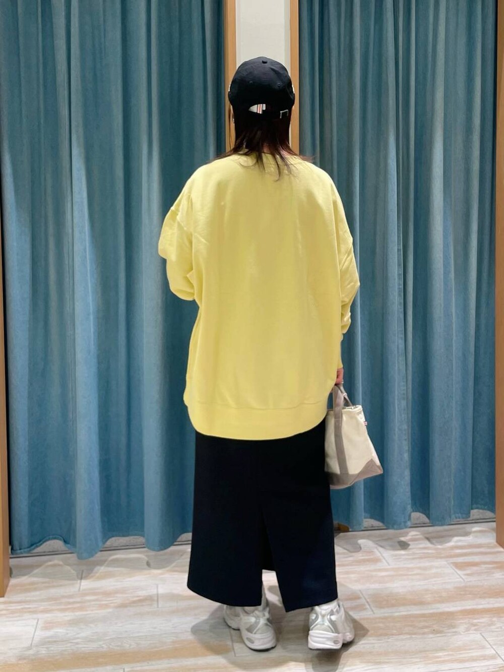 イエロー系のスウェット、ブラック系のスカート、グレー系のトートバッグを着用したレディースの冬コーディネートの3枚目の写真