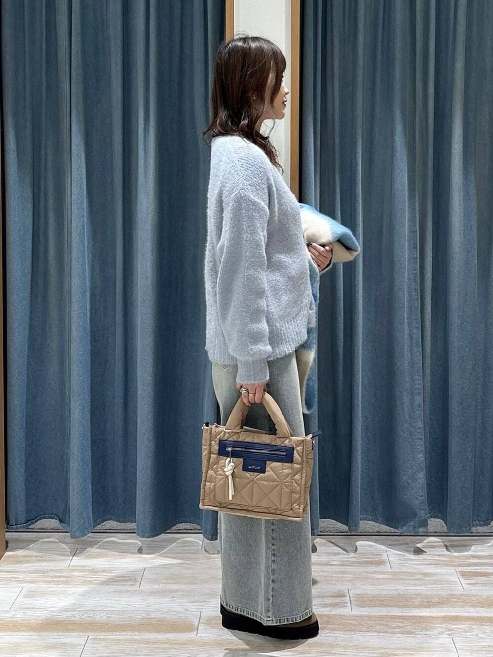 ベージュ系のショルダーバッグ、ホワイト系のTシャツ/カットソー、ベージュ系のブーツを着用したレディースの秋コーディネートの2枚目の写真