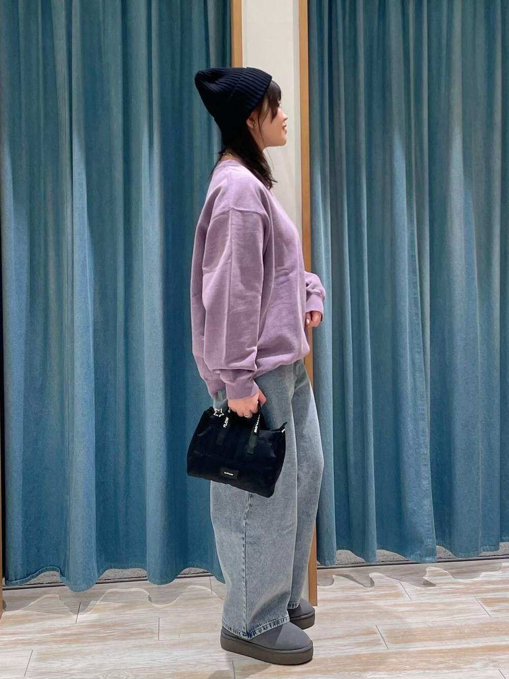 パープル系のスウェット、グレー系のブーツ、ブルー系のデニムパンツを着用したレディースの冬コーディネートの2枚目の写真