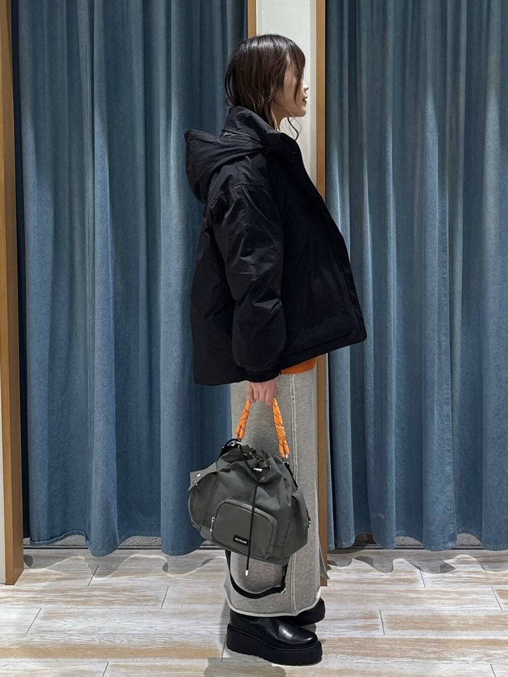 ブラック系のブーツ、グリーン系のハンドバッグ、ブラック系のダウンジャケット/コートを着用したレディースの冬コーディネートの2枚目の写真