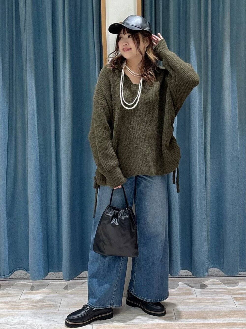 ブラック系のローファー、ブルー系のデニムパンツ、ブラック系のハンドバッグを着用したレディースの秋コーディネートの4枚目の写真