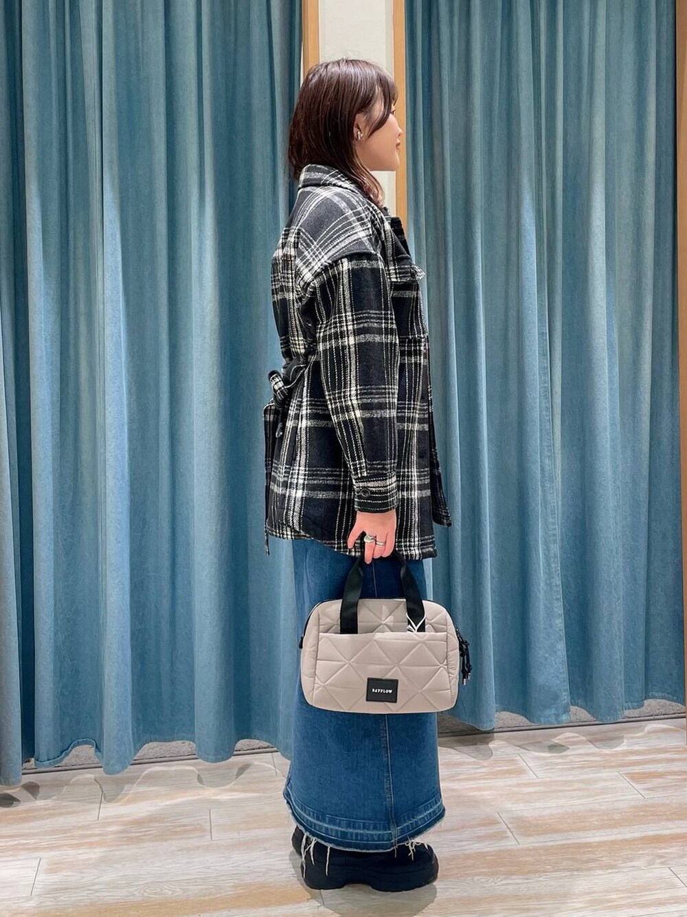 ブルー系のデニムスカート、レッド系のニット/セーター、ブラック系のブーツを着用したレディースの冬コーディネートの2枚目の写真