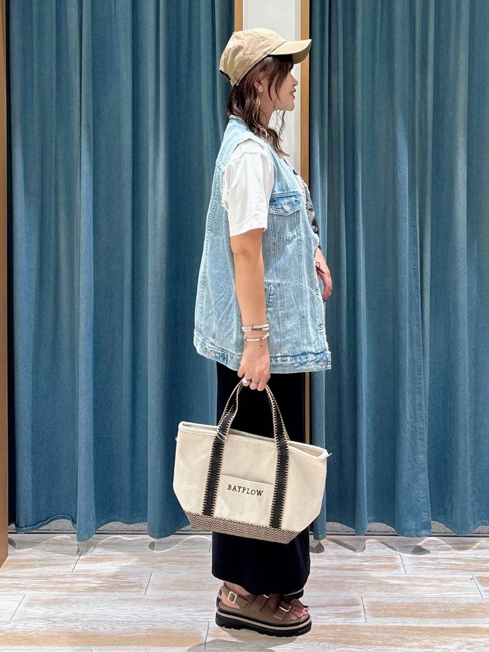 ベージュ系のトートバッグ、ベージュ系のサンダル、ホワイト系のTシャツ/カットソーを着用したレディースの夏コーディネートの2枚目の写真