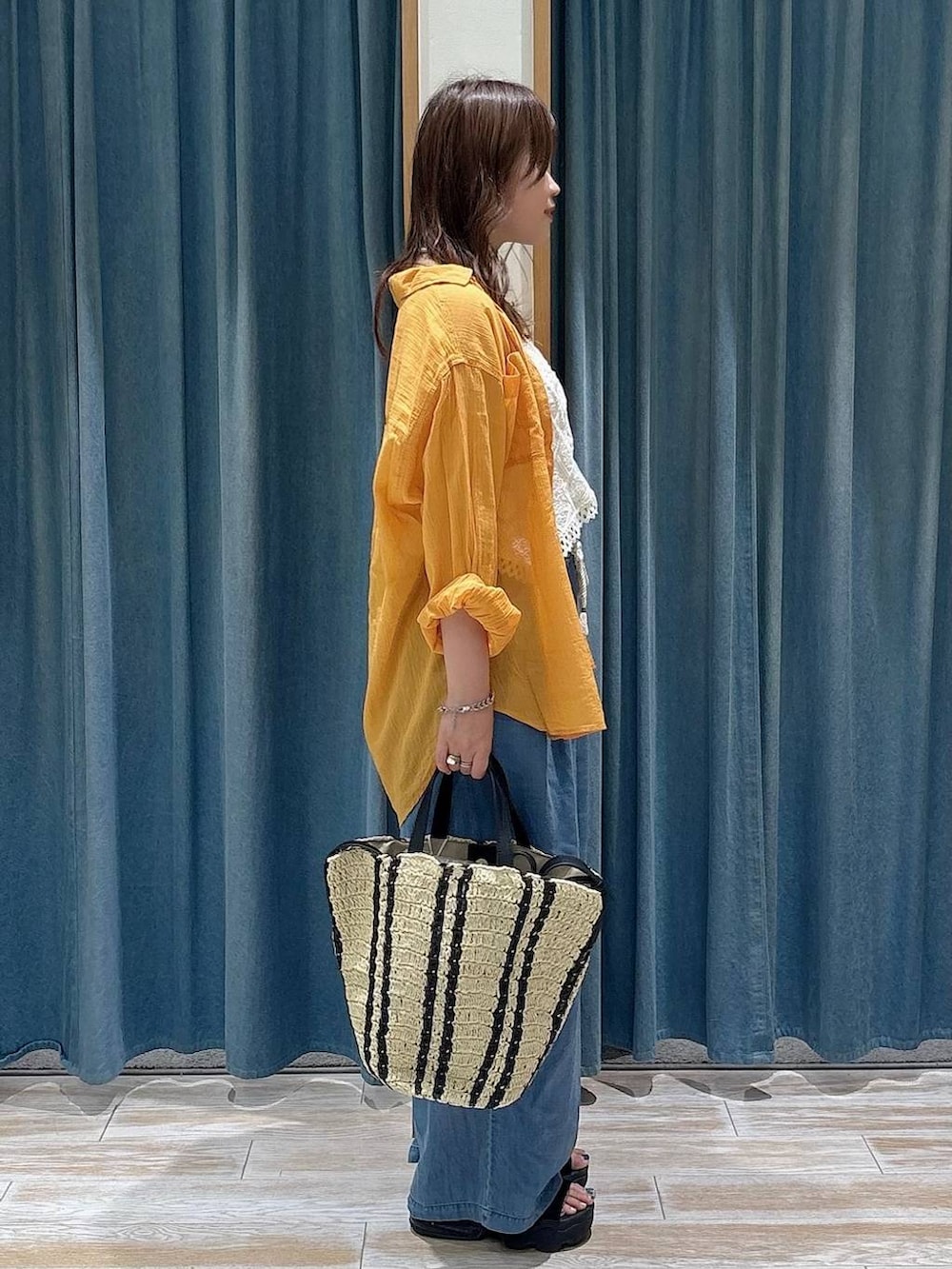 オレンジ系のシャツ/ブラウス、ブルー系のデニムパンツ、ベージュ系のトートバッグを着用したレディースの春コーディネートの2枚目の写真