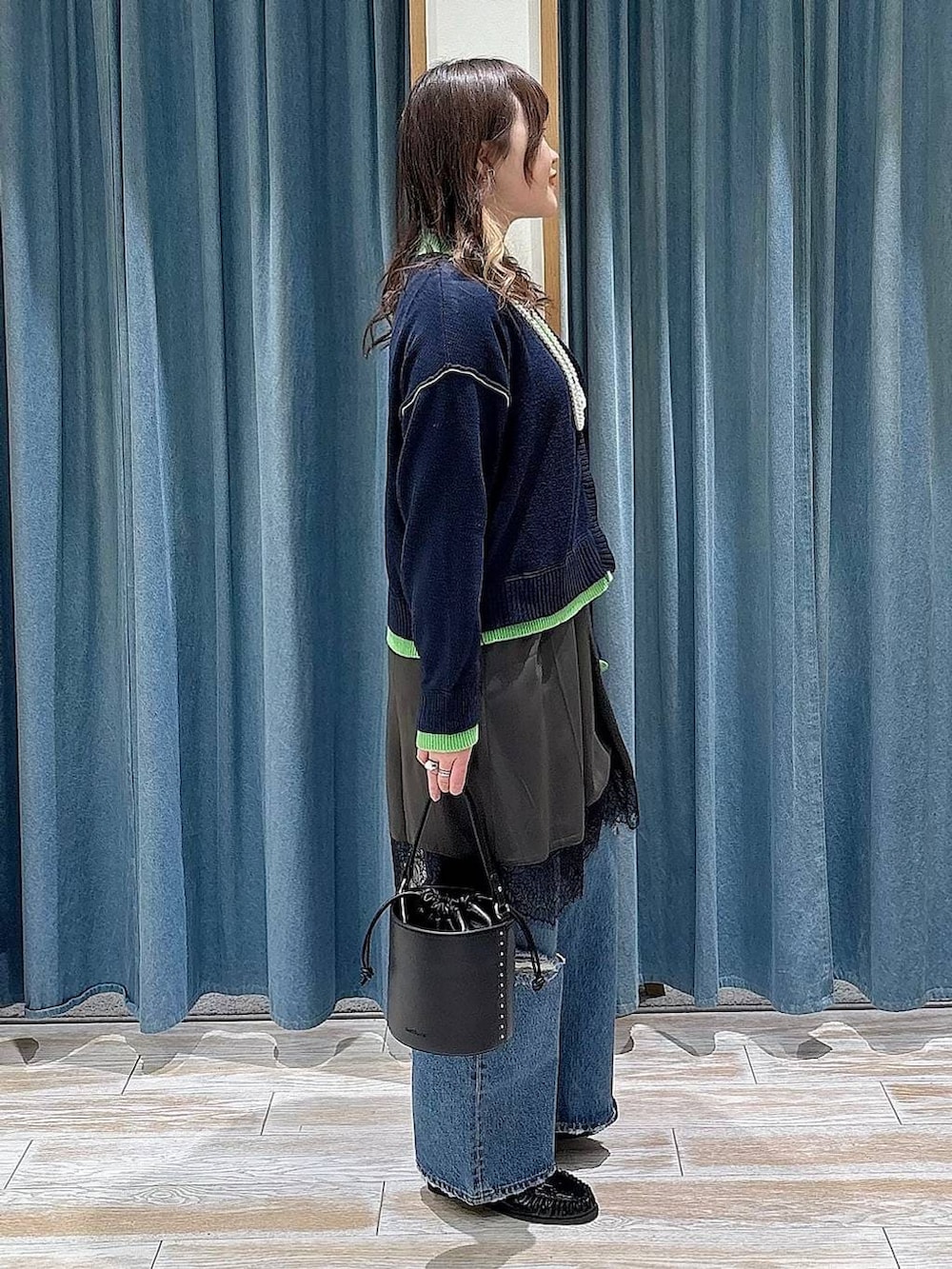 ブラック系のハンドバッグ、ブルー系のデニムパンツ、ブラック系のローファーを着用したレディースの冬コーディネートの3枚目の写真