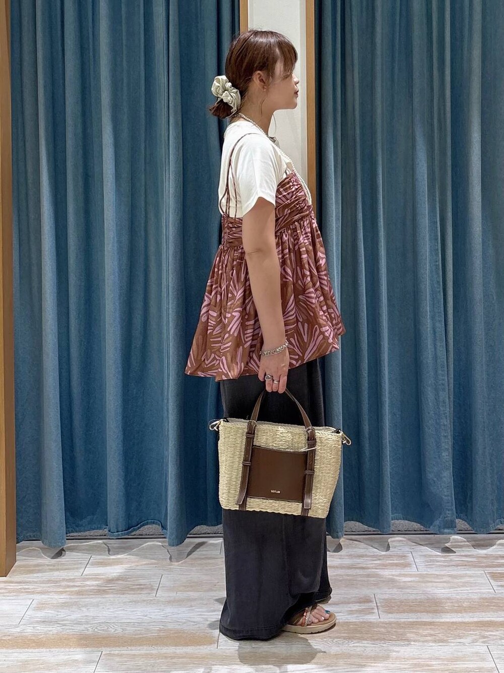 ブラック系のデニムパンツ、ブラウン系のショルダーバッグ、ゴールド系のサンダルを着用したレディースの夏コーディネートの2枚目の写真