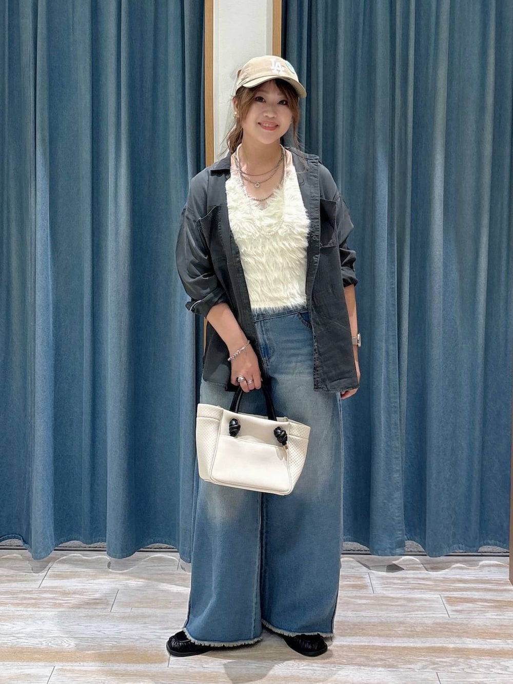 ブラック系のスリッポン、ホワイト系のベスト、ブルー系のデニムパンツを着用したレディースの夏コーディネートの4枚目の写真