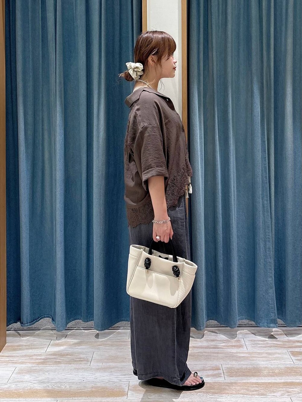 ブラック系のデニムパンツ、ブラック系のサンダル、ベージュ系のショルダーバッグを着用したレディースの夏コーディネートの2枚目の写真