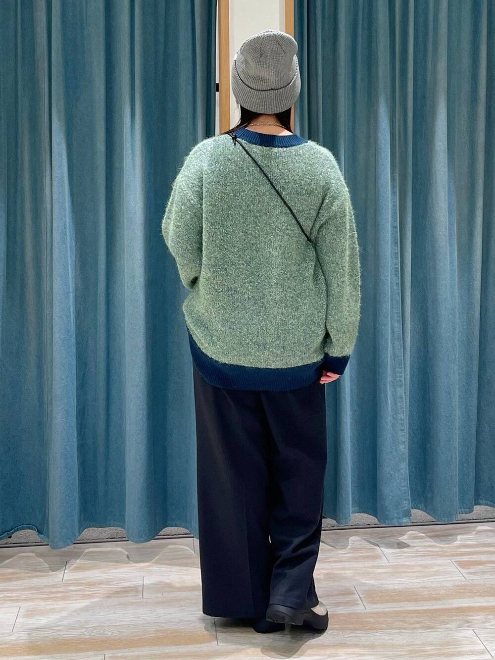 グレー系のショルダーバッグ、ホワイト系のブーツ、グリーン系のニット/セーターを着用したレディースの冬コーディネートの3枚目の写真