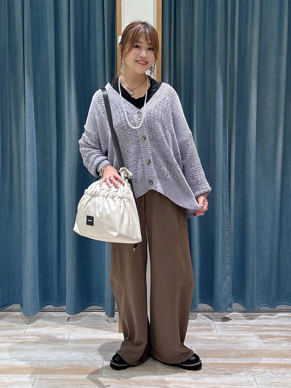 パープル系のカーディガン/ボレロ、ブラウン系のスウェットパンツ、ホワイト系のトートバッグを着用したレディースの秋コーディネートの4枚目の写真