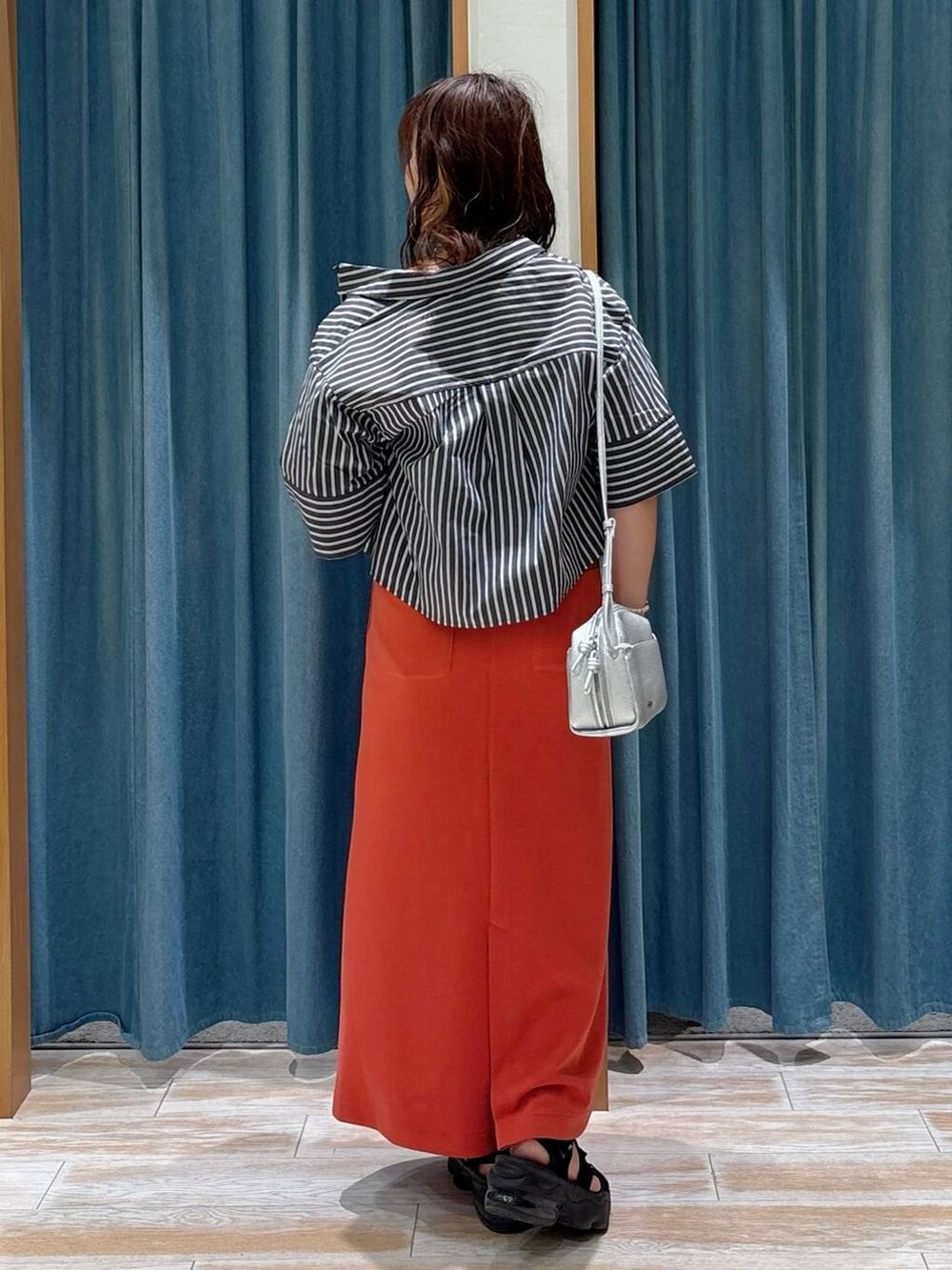 ブラック系のキャミソール、レッド系のスカート、シルバー系のショルダーバッグを着用したレディースの夏コーディネートの3枚目の写真