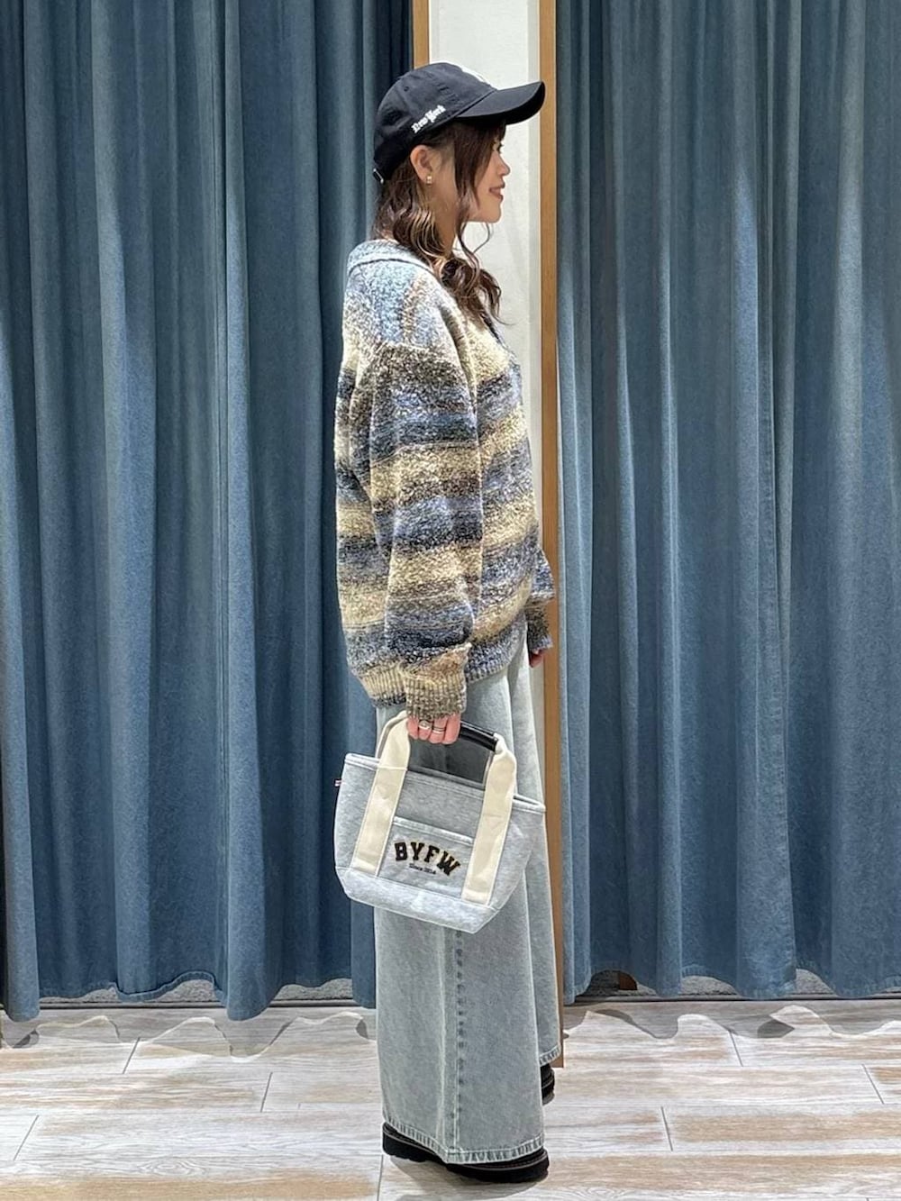 ブラック系のローファー、グレー系のトートバッグ、ブルー系のデニムパンツを着用したレディースの冬コーディネートの2枚目の写真