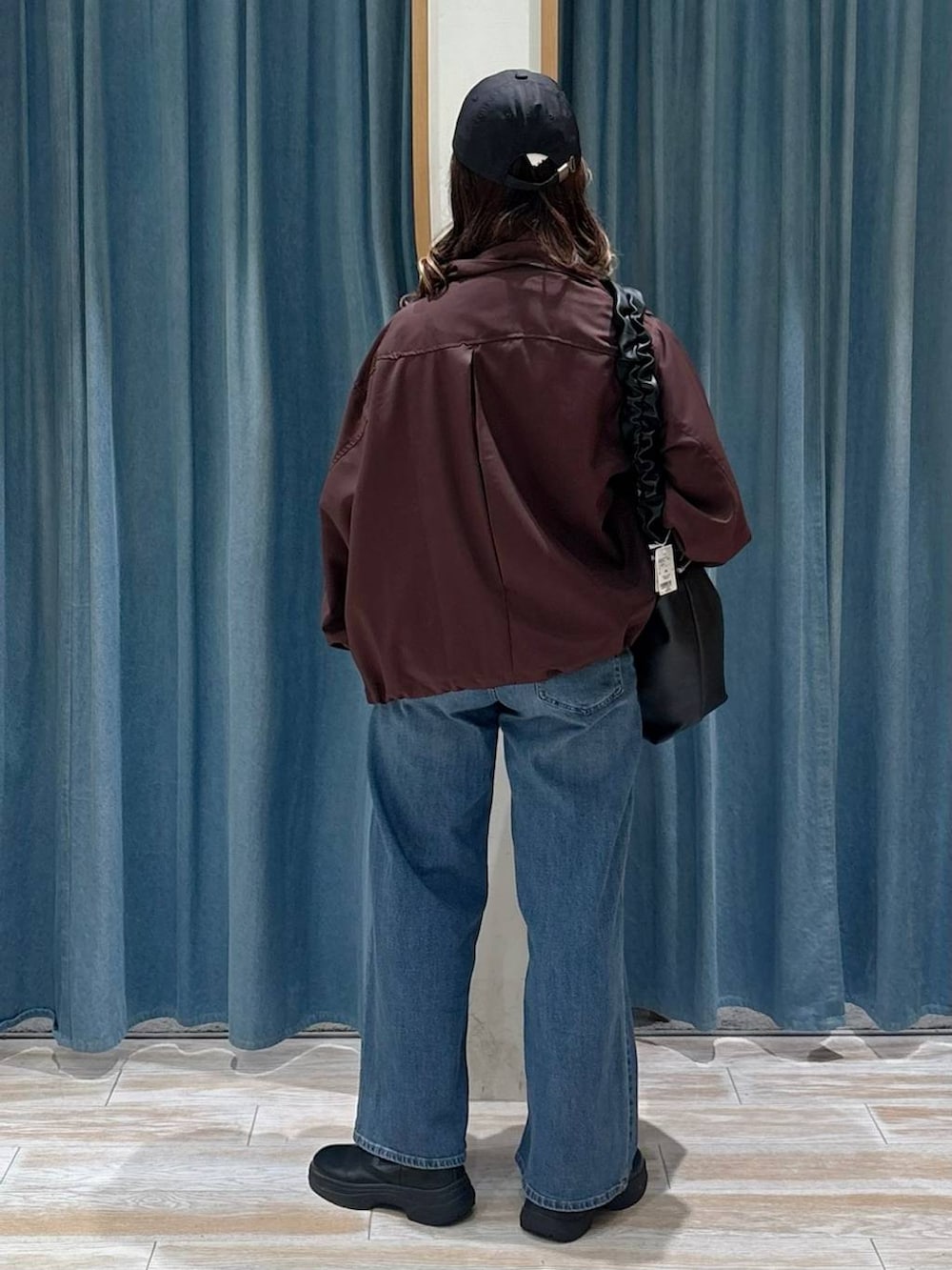 ブラック系のブーツ、ブルー系のデニムパンツ、ブラック系のショルダーバッグを着用したレディースの秋コーディネートの3枚目の写真