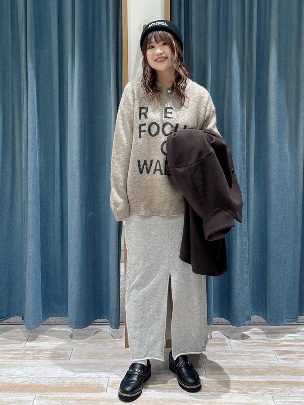 ブラウン系のチェスターコート、ブラック系のローファー、ブラウン系のニット/セーターを着用したレディースの冬コーディネートの4枚目の写真