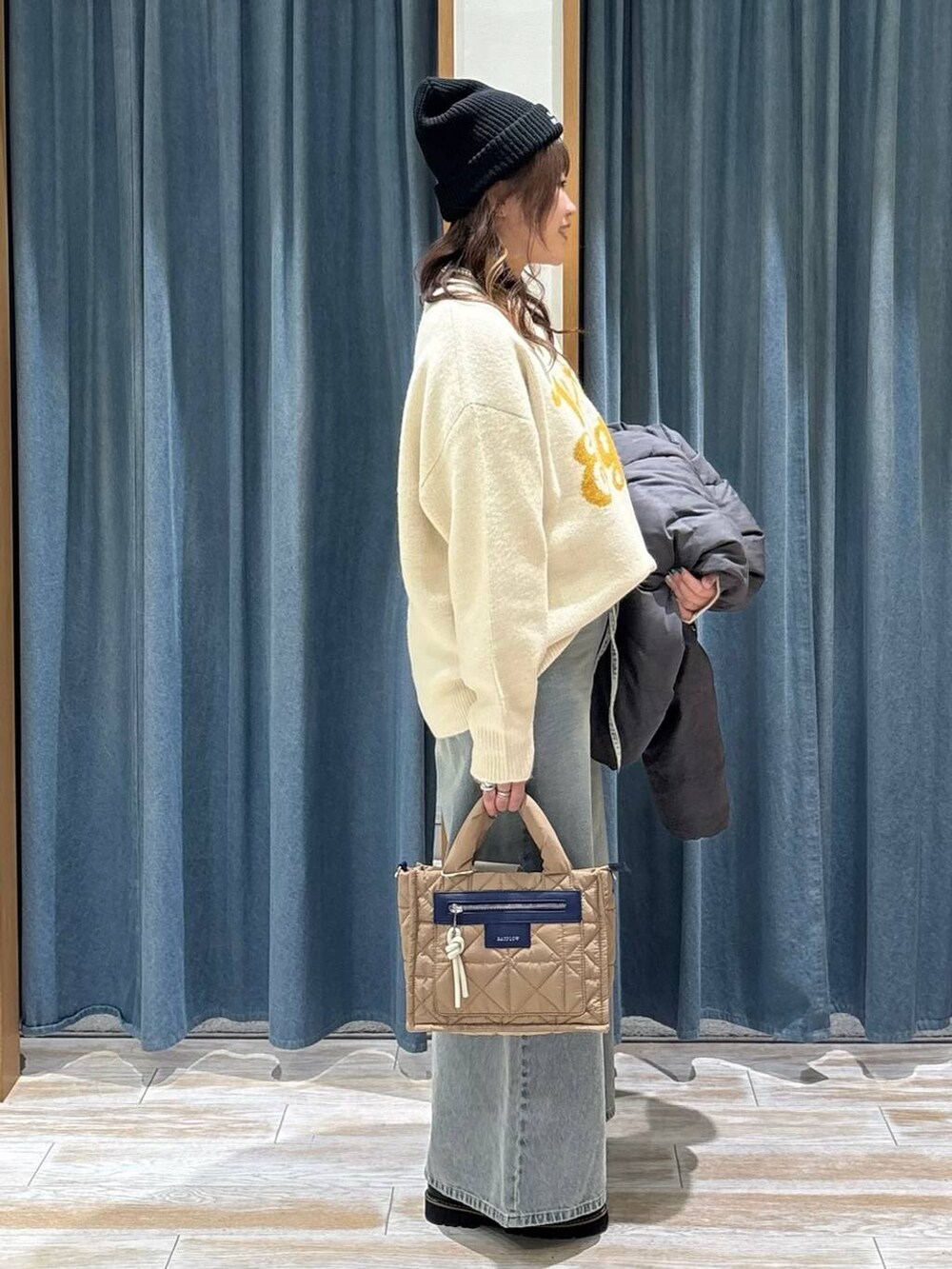 ベージュ系のショルダーバッグ、グレー系のダウンジャケット/コート、ブラック系のローファーを着用したレディースの秋コーディネートの2枚目の写真