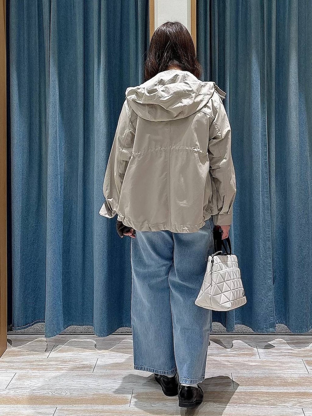 ベージュ系のトートバッグ、ベージュ系のマウンテンパーカー、ブルー系のデニムパンツを着用したレディースの春コーディネートの3枚目の写真